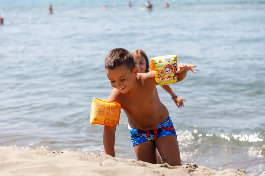 Enfant portant des brassards jouant au bord de l'eau sur une plage